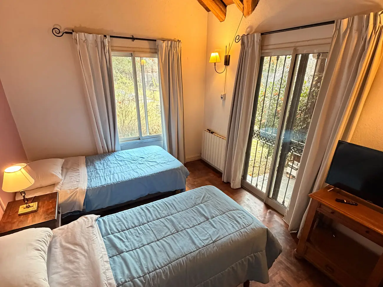 Habitación con techo de vigas de madera y camas con vista al parque